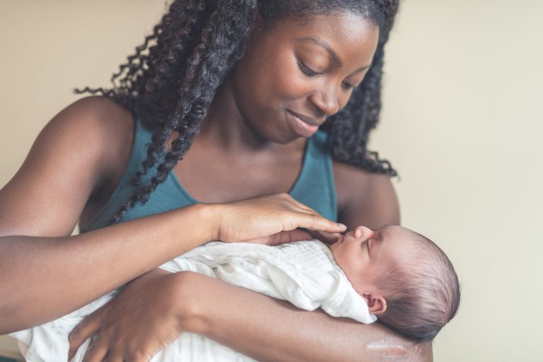 Photograph of a black mom holding an infant lovingly