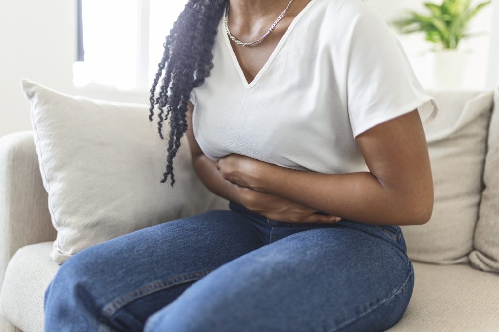 African American Woman holding hands against belly seemingly in pain